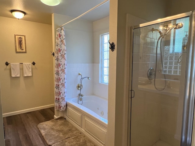 bathroom with wood finished floors, a stall shower, a garden tub, and baseboards