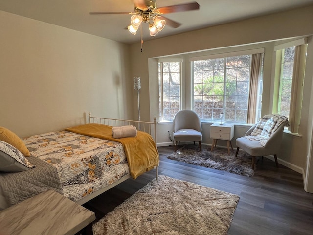 bedroom featuring ceiling fan, dark wood-type flooring, and multiple windows