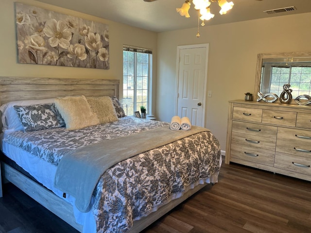 bedroom featuring ceiling fan, visible vents, dark wood finished floors, and multiple windows