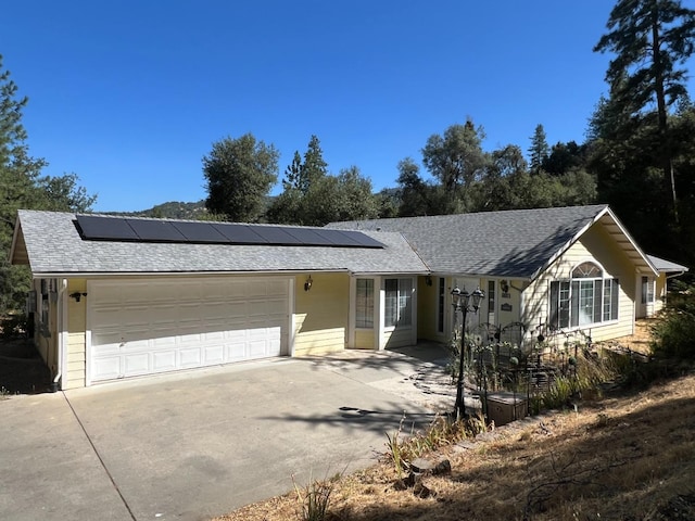 ranch-style house with solar panels and a garage