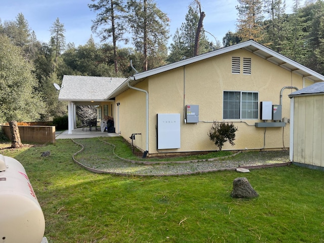 rear view of property with a patio area, a yard, and stucco siding