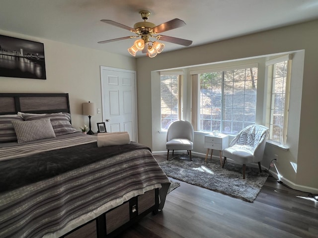 bedroom with dark wood-style floors, ceiling fan, and baseboards