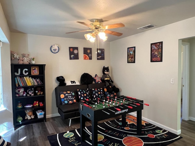 rec room featuring dark wood-style floors, baseboards, visible vents, and ceiling fan