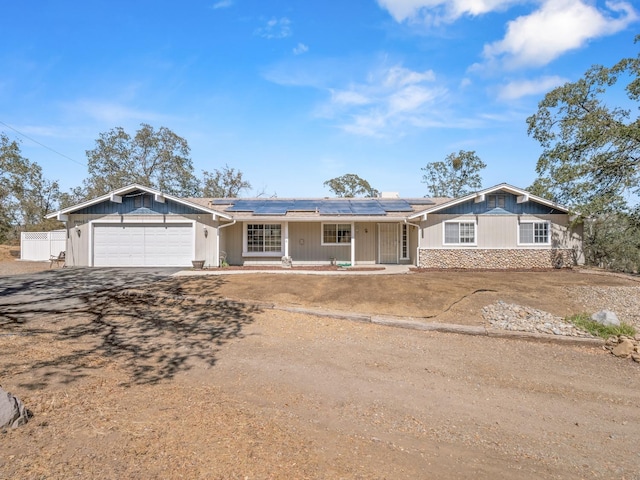 ranch-style home with solar panels, a garage, and a porch