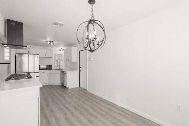 kitchen with sink, appliances with stainless steel finishes, white cabinetry, extractor fan, and a chandelier