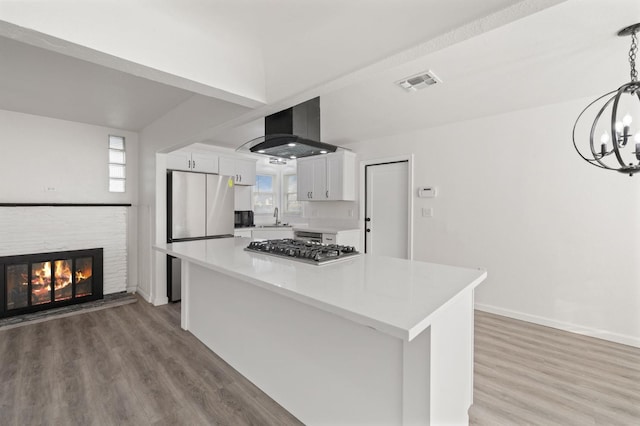 kitchen with pendant lighting, a center island, sink, island range hood, and white cabinetry