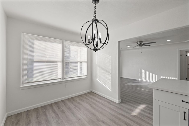 unfurnished dining area featuring light hardwood / wood-style floors and ceiling fan with notable chandelier