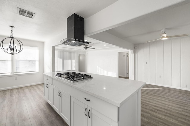 kitchen featuring white cabinets, hanging light fixtures, a kitchen island, island range hood, and stainless steel gas cooktop