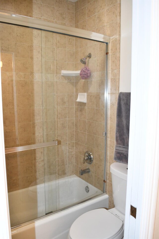 bathroom featuring shower / bath combination with glass door and toilet