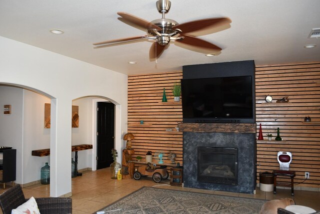 living room featuring a tiled fireplace, ceiling fan, and light tile patterned flooring