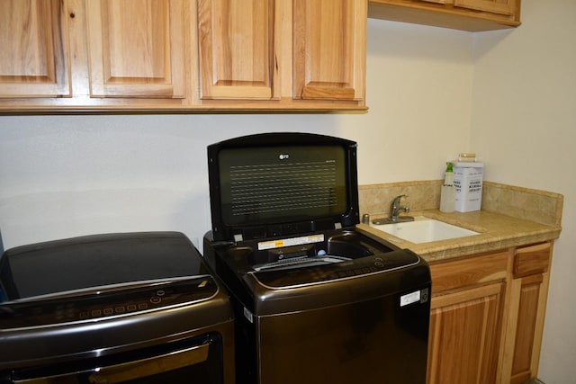 clothes washing area featuring washer / clothes dryer, sink, and cabinets