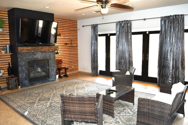 living room with ceiling fan, light tile patterned flooring, a tile fireplace, and french doors