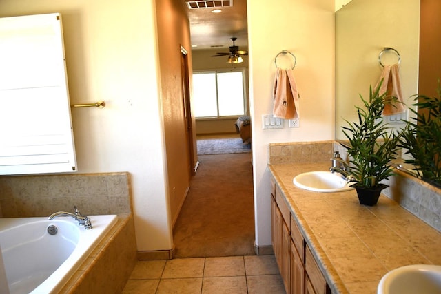 bathroom with tile patterned floors, vanity, ceiling fan, and tiled tub