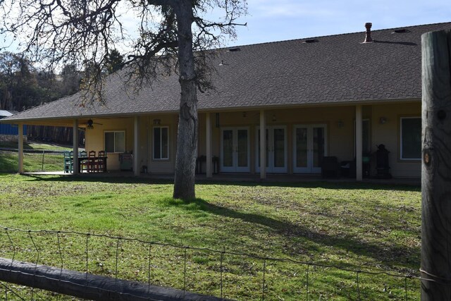 rear view of house featuring ceiling fan, a yard, and french doors