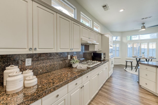 kitchen with white appliances, plenty of natural light, white cabinets, decorative backsplash, and light wood-type flooring