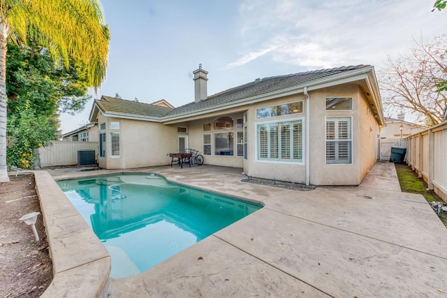 back of house featuring cooling unit, a fenced in pool, and a patio area