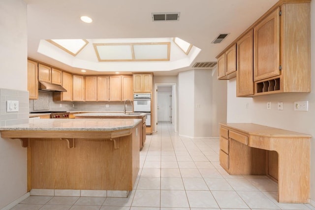 kitchen with kitchen peninsula, light brown cabinetry, and light tile patterned floors