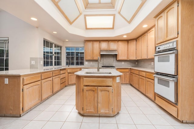 kitchen featuring kitchen peninsula, white double oven, a raised ceiling, sink, and light tile patterned floors