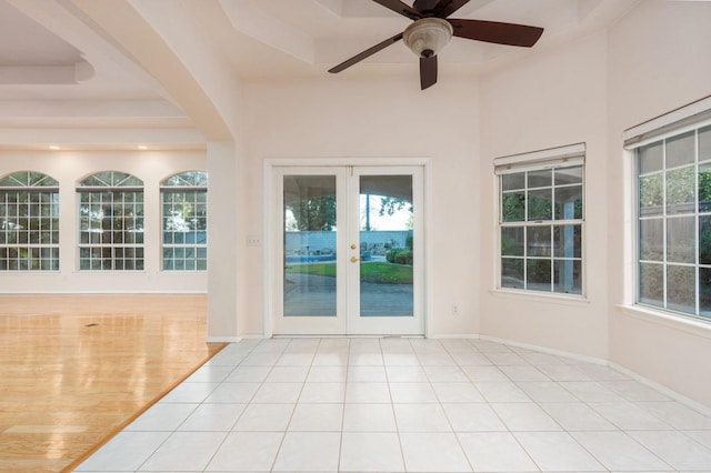 unfurnished sunroom with french doors, a raised ceiling, and ceiling fan