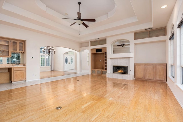 unfurnished living room featuring a fireplace, a tray ceiling, built in features, and sink