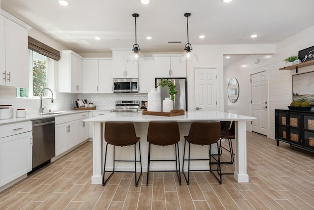 kitchen featuring light countertops, a center island, white cabinetry, a breakfast bar area, and appliances with stainless steel finishes