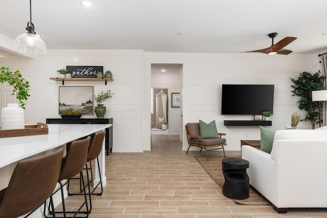 living room with wood walls, recessed lighting, light wood-style flooring, and ceiling fan