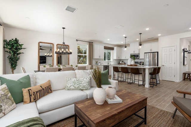 living area with an inviting chandelier, visible vents, and recessed lighting