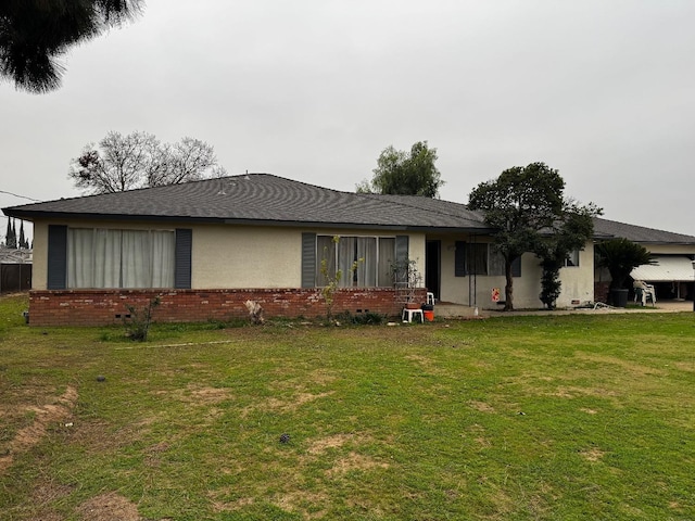 view of front of house with brick siding, a front lawn, and stucco siding