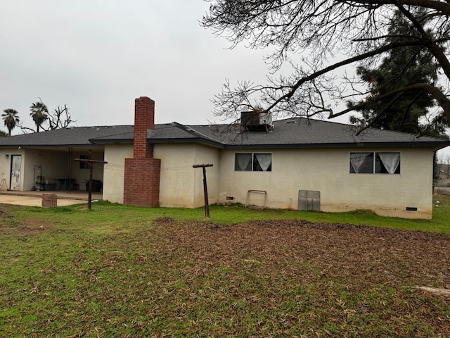 back of property featuring a patio, a lawn, and stucco siding