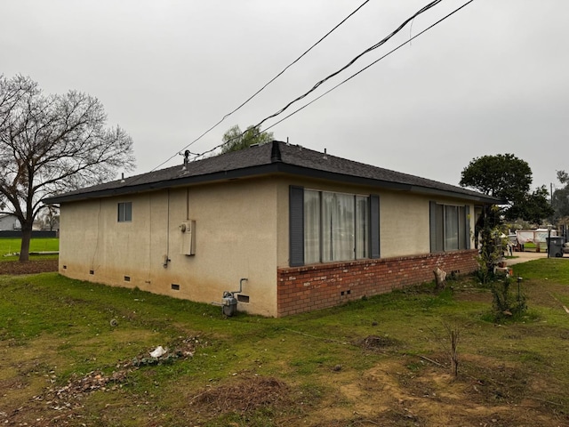 view of side of home featuring crawl space, brick siding, a yard, and stucco siding