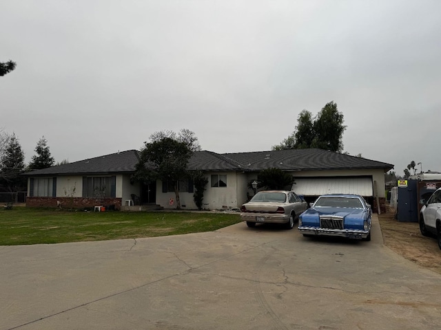 ranch-style home featuring driveway, an attached garage, a front lawn, and stucco siding