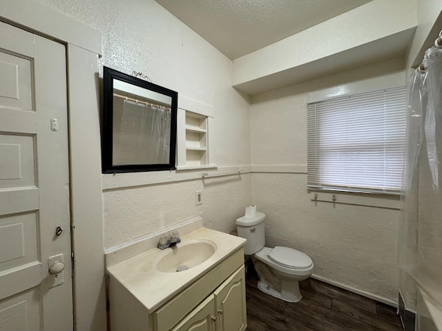 bathroom featuring vanity, hardwood / wood-style flooring, toilet, a textured ceiling, and walk in shower