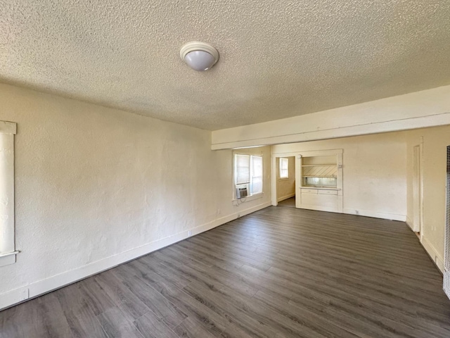 spare room with dark hardwood / wood-style floors, cooling unit, and a textured ceiling