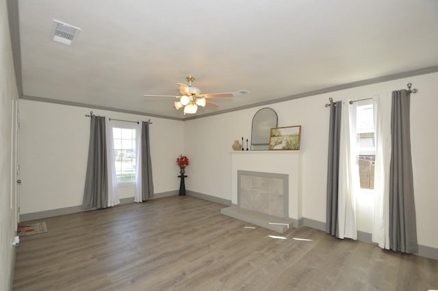 unfurnished living room with hardwood / wood-style flooring, ceiling fan, ornamental molding, and a tile fireplace