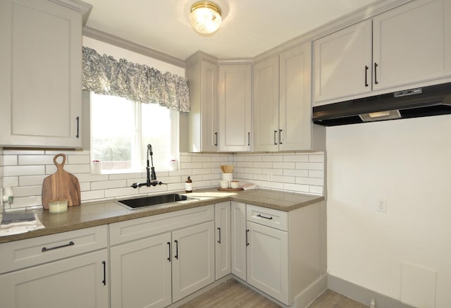 kitchen featuring white cabinets, light hardwood / wood-style floors, sink, and tasteful backsplash