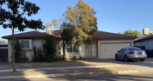 ranch-style home featuring central AC and a garage