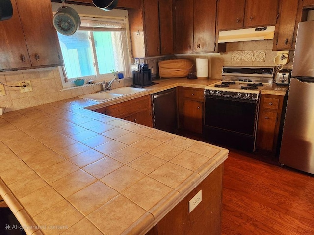 kitchen featuring appliances with stainless steel finishes, tasteful backsplash, tile counters, and sink