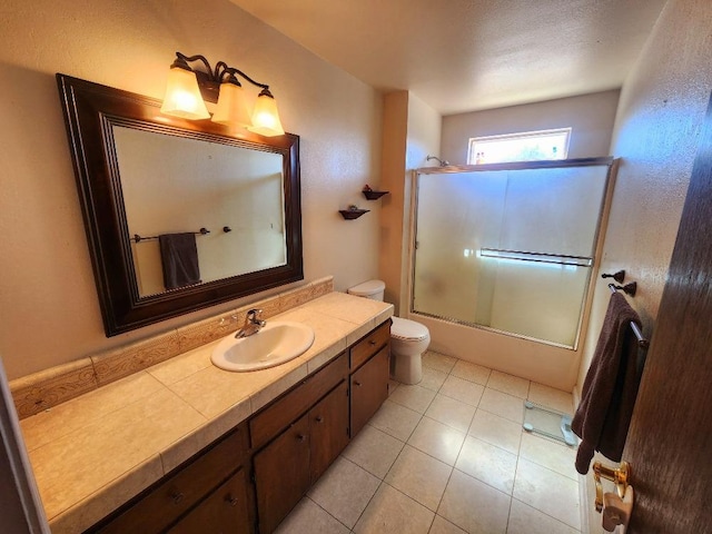 full bathroom featuring combined bath / shower with glass door, tile patterned floors, vanity, and toilet