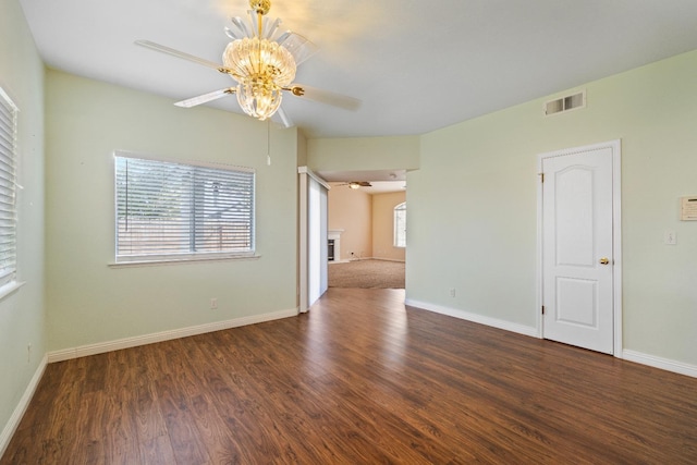 empty room featuring ceiling fan, a healthy amount of sunlight, and dark wood-type flooring