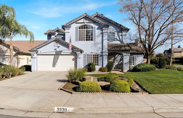 traditional-style home featuring an attached garage, a tile roof, stucco siding, a front yard, and driveway
