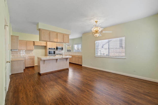 kitchen with a center island, light brown cabinets, a kitchen breakfast bar, decorative backsplash, and appliances with stainless steel finishes