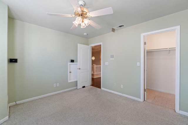 unfurnished bedroom featuring ceiling fan, light colored carpet, a spacious closet, and a closet