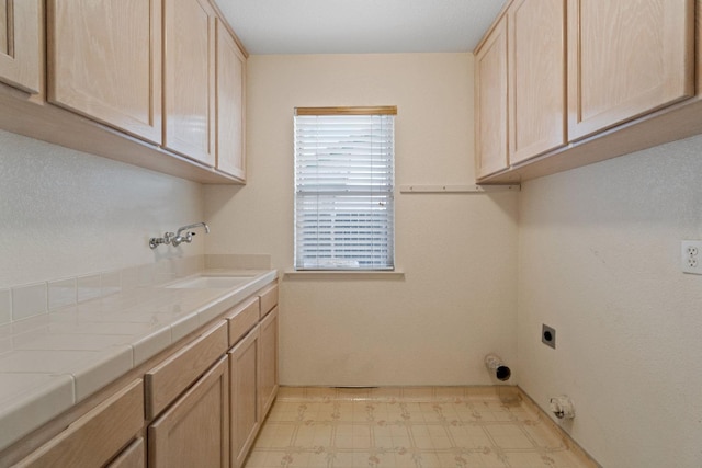 washroom with cabinets, electric dryer hookup, and sink