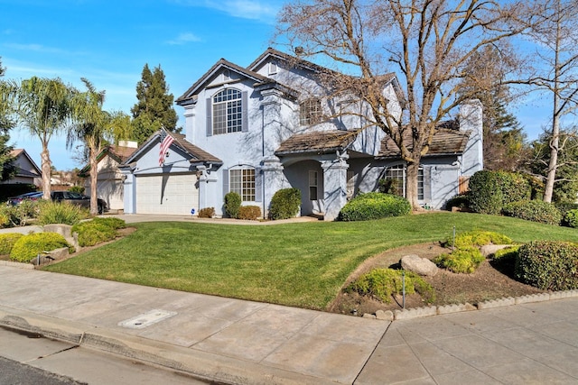 traditional home featuring a garage, stucco siding, concrete driveway, and a front lawn