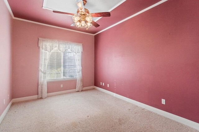 empty room featuring carpet floors, a ceiling fan, crown molding, and baseboards