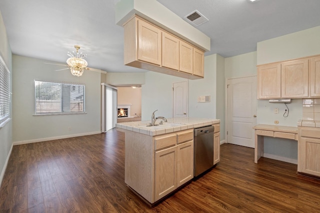 kitchen with tile counters, sink, stainless steel dishwasher, an island with sink, and light brown cabinetry