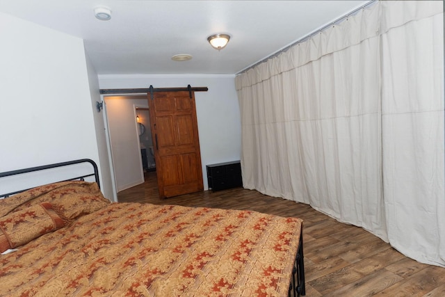 bedroom with a barn door and dark hardwood / wood-style flooring