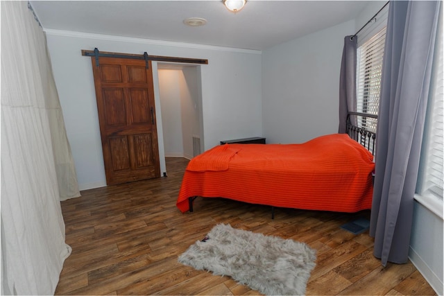 bedroom featuring a barn door, dark hardwood / wood-style flooring, and ornamental molding