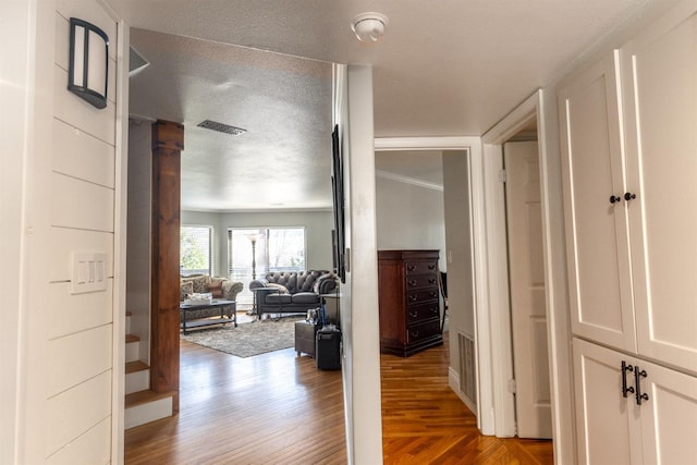 hall with a textured ceiling and light hardwood / wood-style flooring
