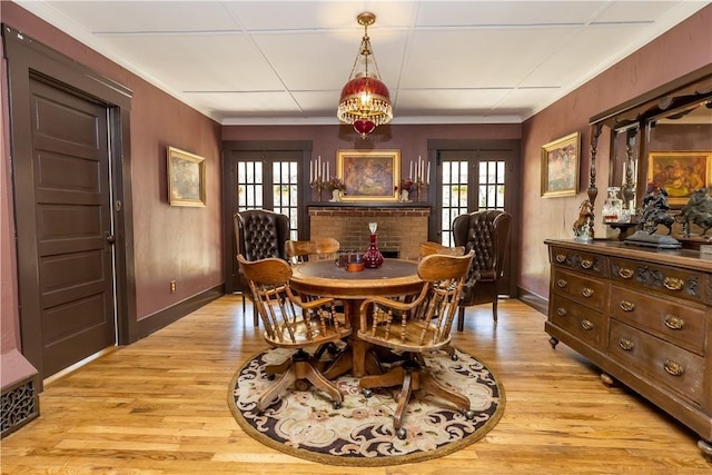 dining room with plenty of natural light, light wood-style flooring, crown molding, and french doors